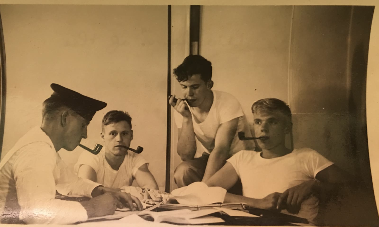 Four young Navy sailors seated around a table smoking pipes; Harold G. Johnson is at far right