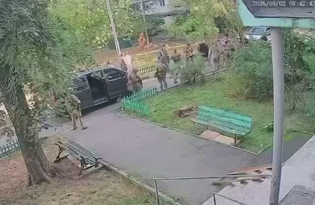 Security-camera view of armed men and a black SUV in a Kyiv courtyard. Select to watch the 51-second video on Four Fingers News.