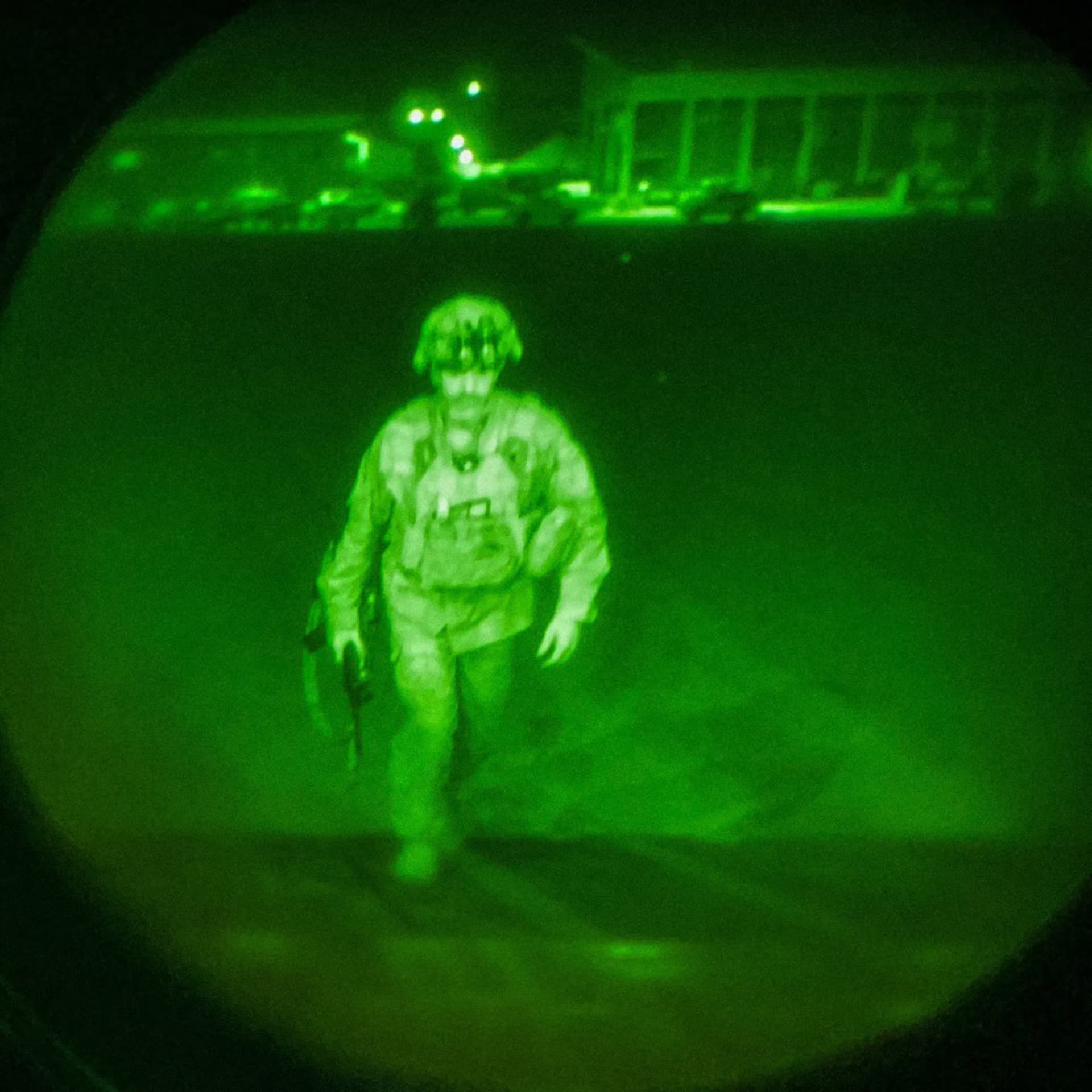 Green night-vision image of Maj. Gen. Chris Donahue crossing the tarmac with Kabul airport buildings behind him