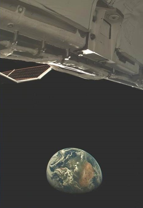 Earth below the visible structure of the X-37B experimental spaceplane, photographed by an onboard camera.